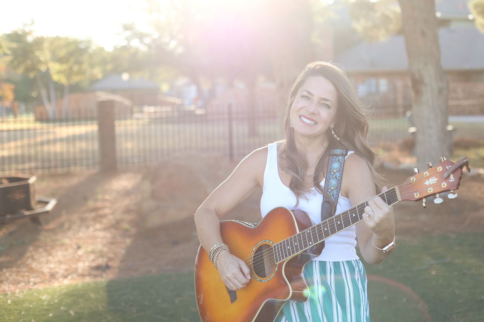 Carrie Gotcher playing her guitar outdoors in the evening sun