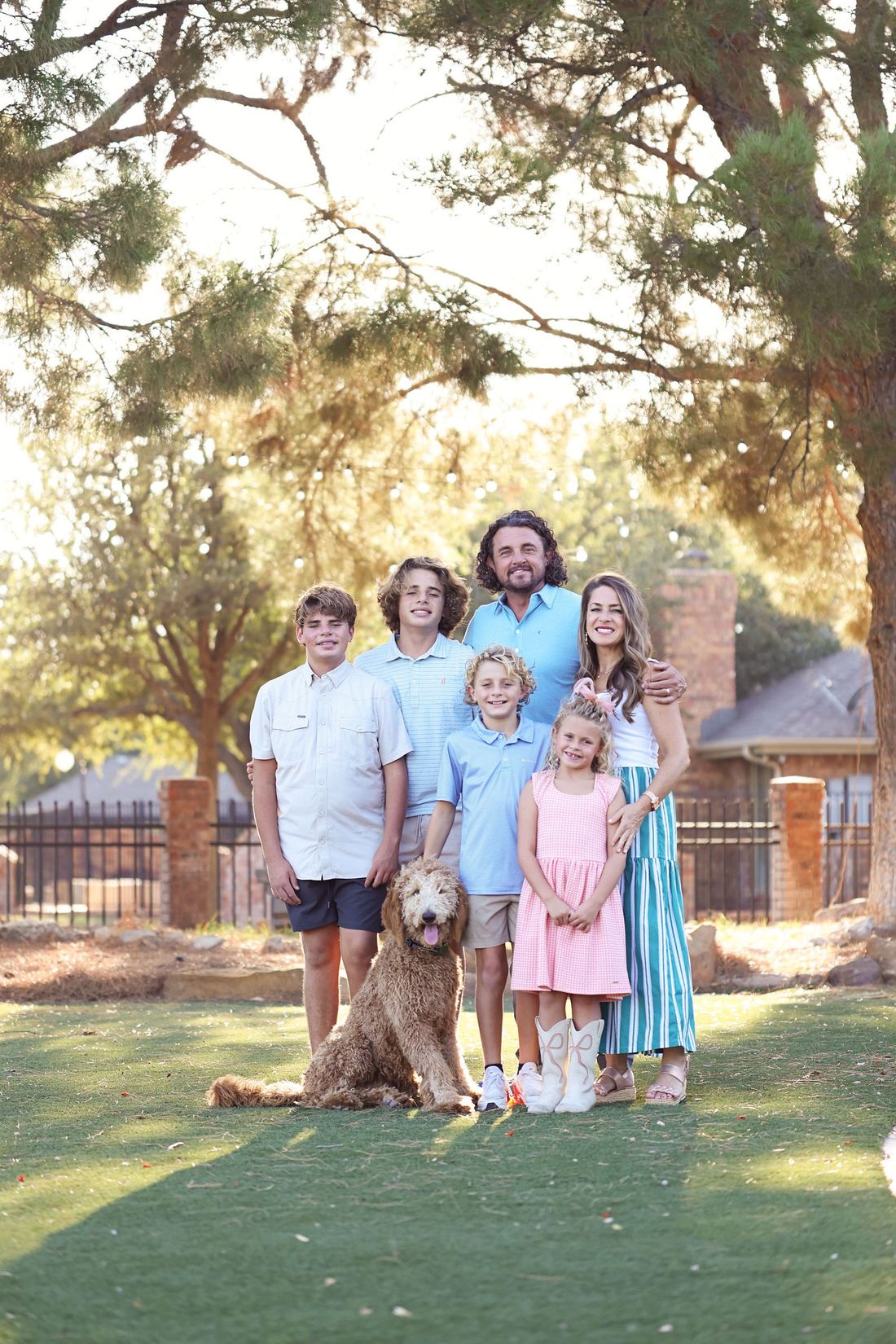 The Gotcher family standing together under the trees with their dog