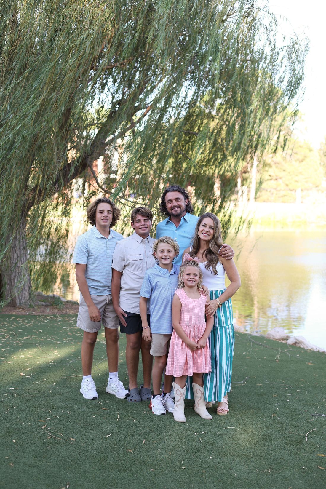 The Gotcher family standing together beside a willow tree and a pond